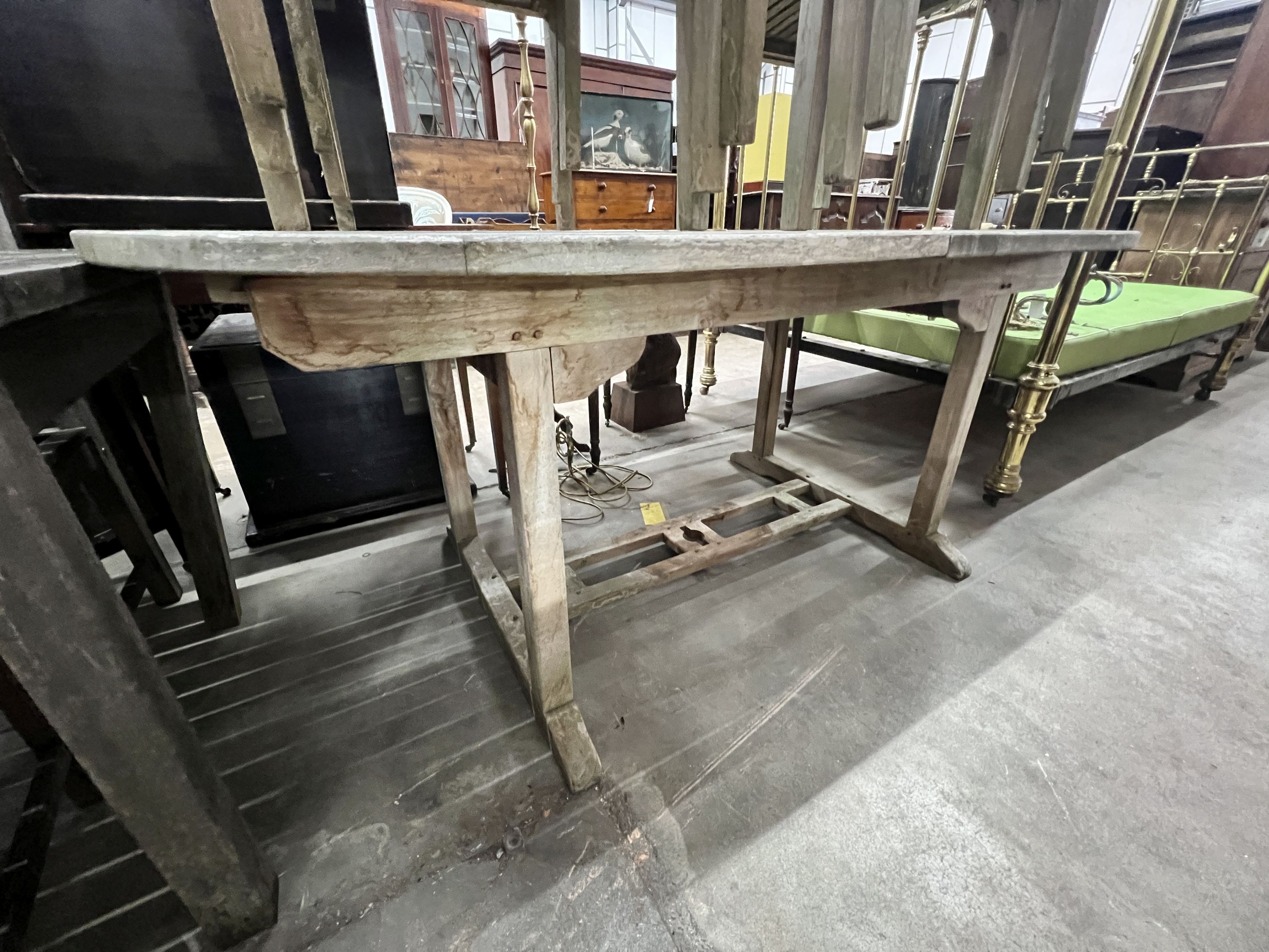 An oval weathered teak extending garden table, width 180cm, depth 100cm, height 76cm and six teak stacking chairs